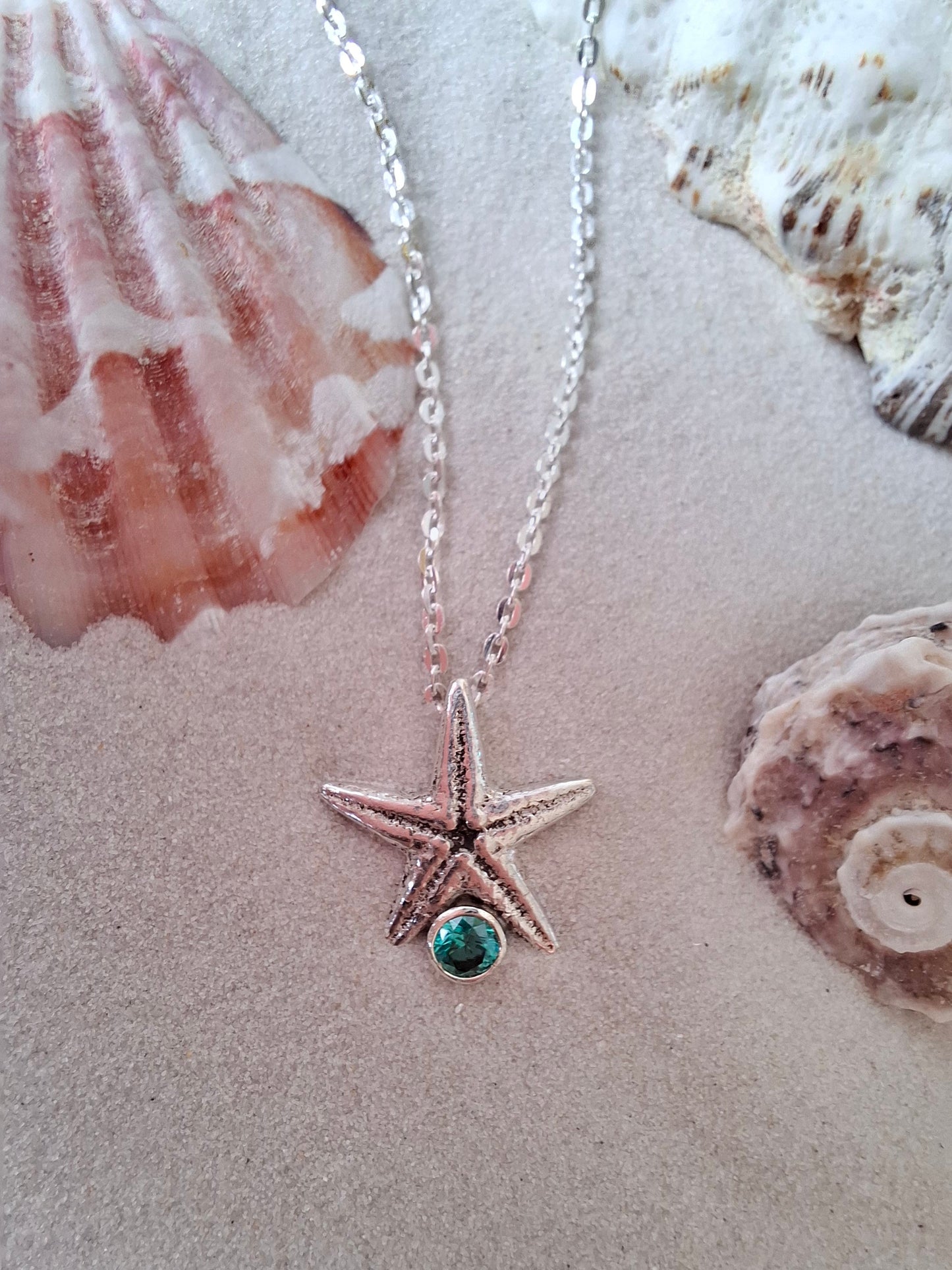 Cast silver starfish pendant with a teal green cubic zirconia, with necklace