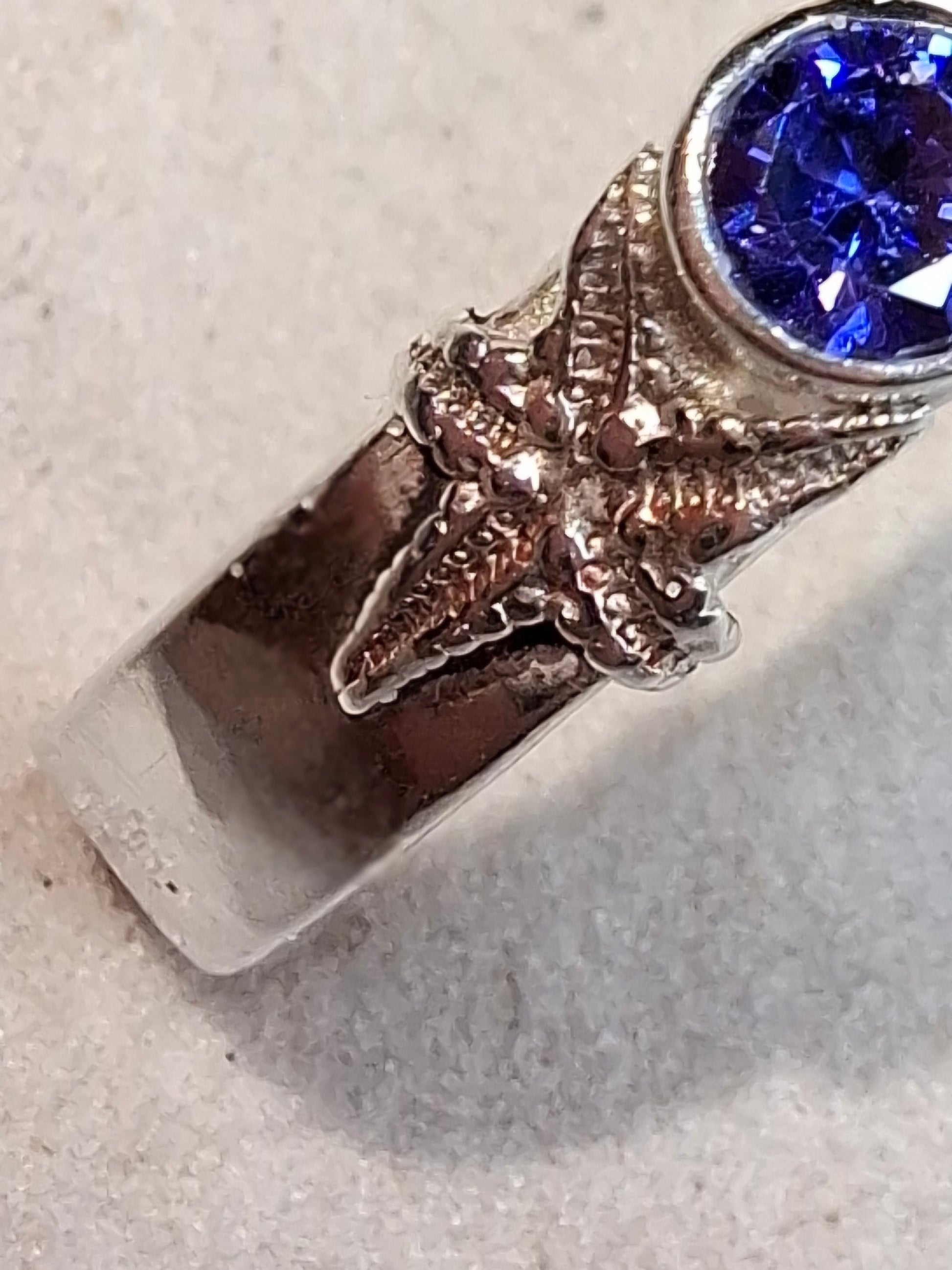 Hammered silver ring featuring a delicate silver starfish and a tanzanite cubic zirconia