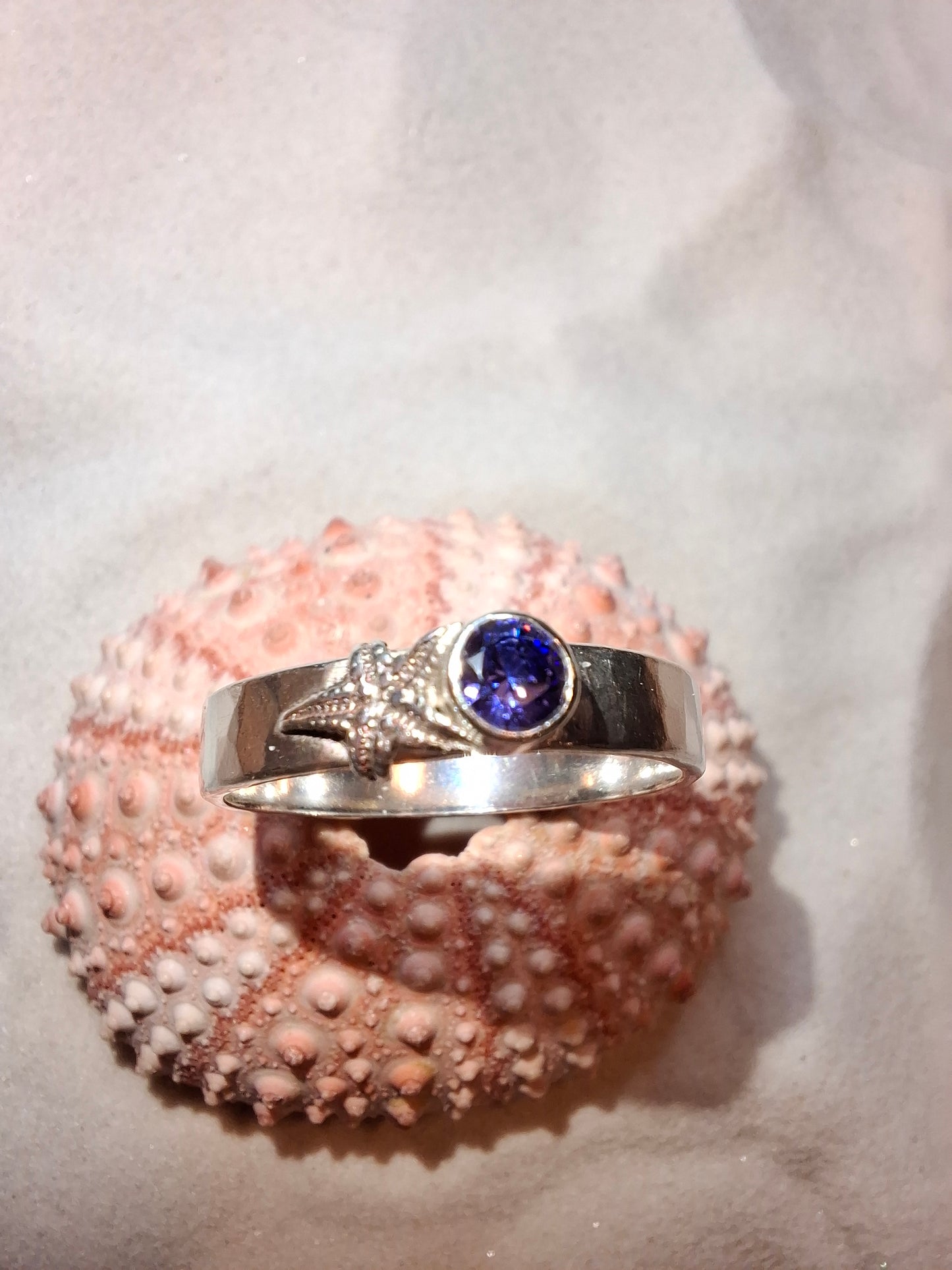 Hammered silver ring featuring a delicate silver starfish and a tanzanite cubic zirconia