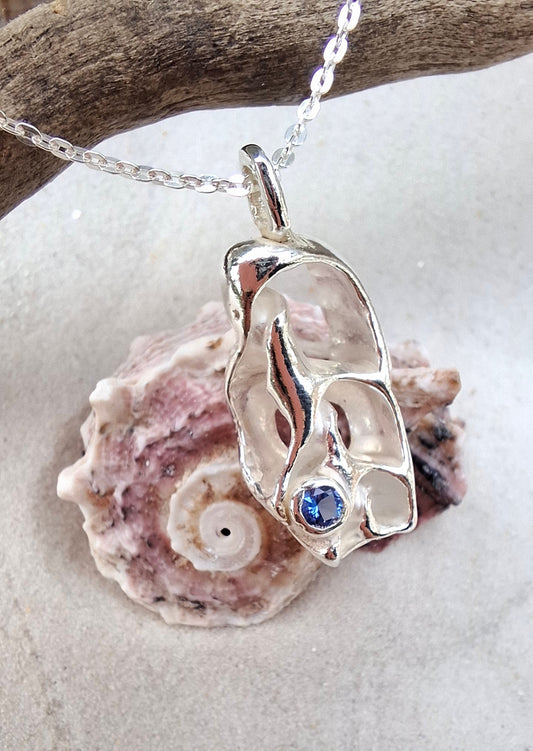 Cast silver seashell pendant with a tanzanite cubic zirconia