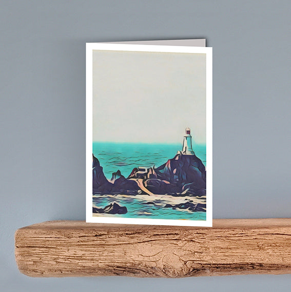 A scenic print on a blank greeting card of a lighthouse on rocks with the green blue sea surrounding it. The lighthouse is Corbiere Lighthouse in Jersey.